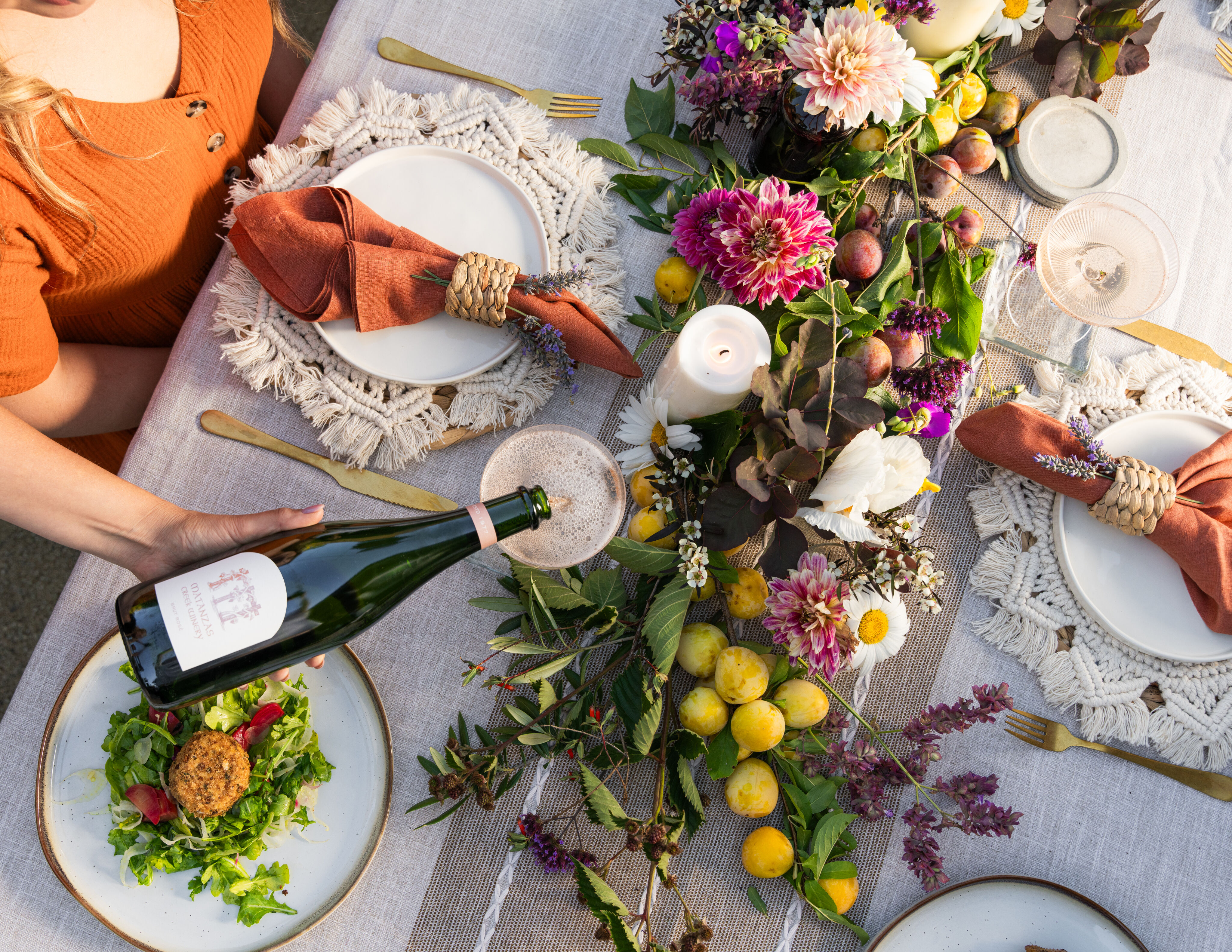 Outdoor image at a picnic bench of a person pouring a glass of Matanzas Creek wine at a farm to table dinner