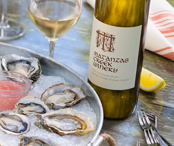 Oysters on a plate with a bottle of white wine to the right.